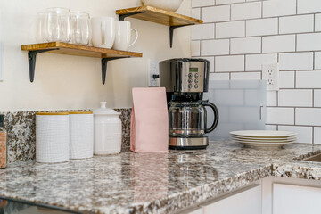 Coffee maker in kitchen corner with ceramic jars plates cups