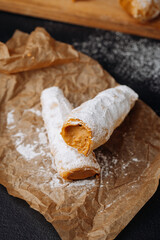 Caramel cream filled pastry rolls dusted with powdered sugar on parchment paper