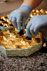 Obraz premium Placing premium handmade chocolates into elegant golden packaging, close up view