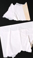 Two pieces of torn white paper on black background