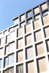 A large and impressive building featuring numerous windows, with a vibrant blue sky beautifully set...