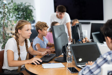 Fototapeta premium Girl student learns to work with computer in group at lesson