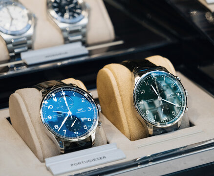 Palma, Spain - Jul 15, 2025: Pair of IWC Portugieser automatic chronograph watches with blue and green dials presented in luxurious beige watch holder inside a boutique store.