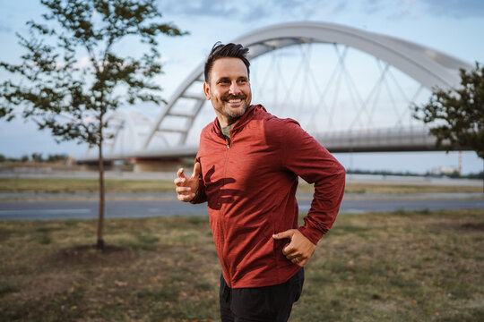 Happy man running near bridge in red sportswear