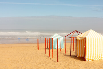 Striped beach tents on golden sand in Santa Cruz, Torres Vedras, Portugal. 10 September 2025