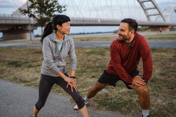 Couple stretching legs together before running in urban environment