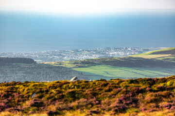 Douglas, Isle of Man 08,05,2023 Beautiful view of a town and ocean with a green hillside. The sky...