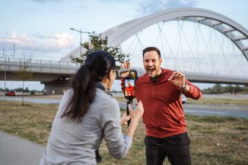 Personal trainer recording outdoor workout with smart phone and gimbals