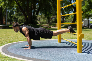 Young man strengthening his body with push-ups in the park