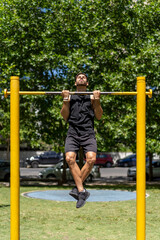 Fit young man executing pull-ups in a park setting