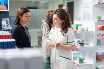 Healthcare worker assisting a pharmacy customer in choosing SPF cream, recommending the best sun...