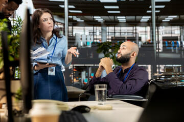 Middle eastern wheelchair user attends a meeting with the colleagues, professional employees discuss about business tasks in a disability friendly workspace. Diverse workers in inclusive space.