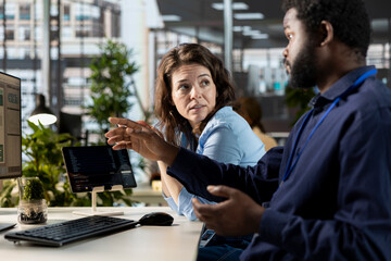 Manager reviews company infographics with a team member in a corporate office, making important organizational decisions to support global expansion. Discuss resource allocation.