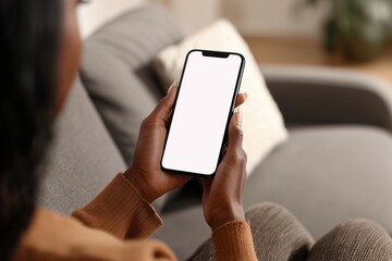 a black woman using a smartphone with a blank screen, sitting on a sofa at home and holding a mobile phone in her hands Generative AI