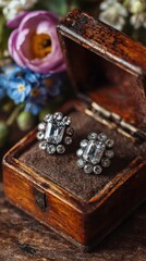 Vintage diamond earrings displayed in an ornate wooden box surrounded by delicate flowers