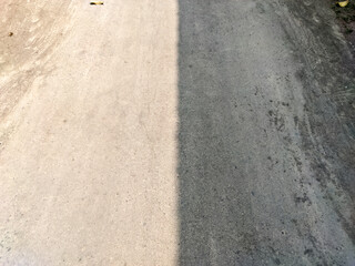 Fototapeta premium A concrete path sharply divided by a distinct line of sunlight and shadow, creating a striking contrast. This abstract image is perfect for themes of light, contrast, and urban geometry.