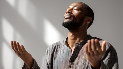 Young man praying with open hands and closed eyes