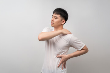 A handsome Asian man exhibiting a pained expression, clutching his upper arm due to severe muscle...
