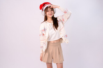 smiling beautiful woman celebrating christmas wearing santa hat and headphones in white studio background