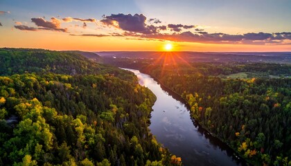 Obraz premium A breathtaking aerial view of a river winding through a vibrant landscape at sunset, showcasing a rich tapestry of autumnal colors and dramatic clouds.