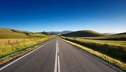 expansive rural road leading towards distant rolling hills under a clear blue sky