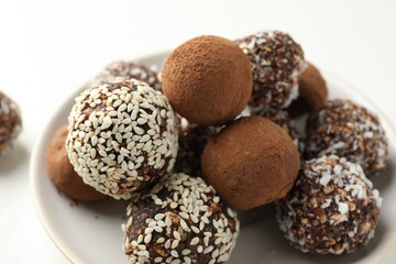 Tasty chocolate candies with cocoa powder, nuts and sesame seeds on table, closeup