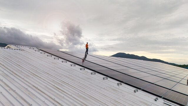 technician installs a large photovoltaic system on an industrial rooftop. ESG investment, and the future of sustainable technology powered by AI energy management and next generation solar cells.