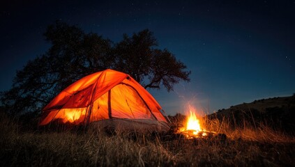 An orange tent glows warmly under a starry night sky, beside a crackling campfire.