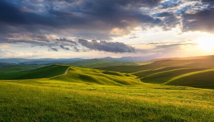 Obraz premium Green Hilltop Landscape Under A Cloudy Sunset Sky