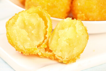 Golden Deep Fried Potato Balls Cut in Half on White Plate