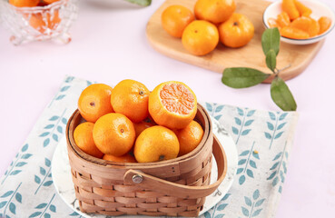 Fresh Baby Mandarin Oranges and Citrus Fruits in Rustic Wicker Basket on White Kitchen Table