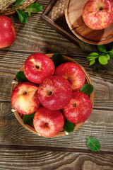 Fresh Red Apples in Wicker Basket on Rustic Wood Table with Green Leaves - Organic Fruit Harvest