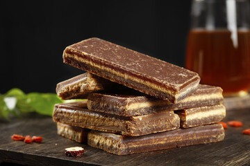 Brown cane sugar blocks stacked on wooden table with traditional tea glass background