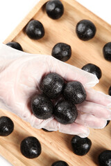Hand Holding Black Sesame Balls - Traditional Handmade Asian Dessert Food on Wooden Board