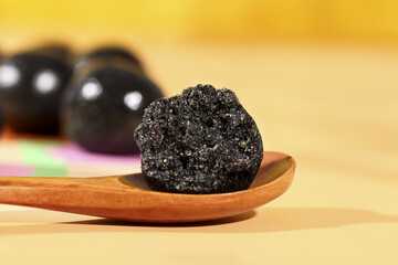 Nutritious Black Sesame Honey Energy Ball Closeup on Wooden Spoon - Healthy Supplement Pill