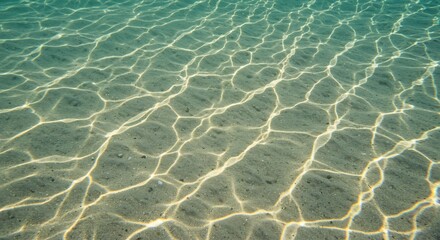 Fototapeta premium Underwater Sandy Seabed with Ripples of Sunlight Patterns in Aqua Water