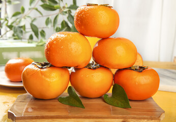 Fresh Ripe Persimmons on Wooden Board in Kitchen Setting