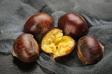 Obraz premium Fresh Roasted Chestnuts with Cracked Shell Showing Golden Interior on Rustic Burlap