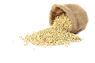Buckwheat groats spilling from burlap sack - healthy whole grain cereal on white background