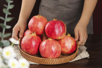 Fresh Red Pomegranates in Wicker Basket Held by Woman's Hands - Healthy Organic Fruit Harvest
