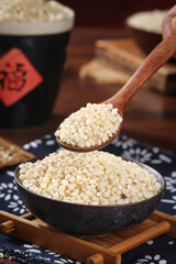 Fresh Sorghum Grain in Wooden Spoon and Bowl on Rustic Kitchen Table