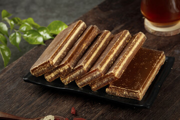 Large handmade brown sugar cubes on slate plate with basil and tea on wooden table