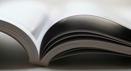 Abstract close-up of an open book with fanned pages, highlighting the interplay of light and shadow. Represents knowledge, learning, and the beauty of literature.