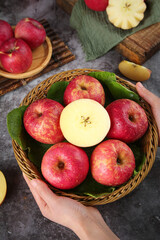 Fresh Red Fuji Apples in Wicker Basket Held by Hands on Rustic Wood Table Top View