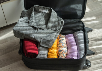 An opened suitcase with colorful clothings pack and arrange inside.