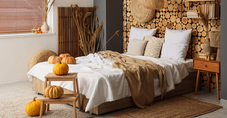 Interior of cozy bedroom with bed, pumpkins and bedside table