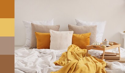 Plaid and tray with tea on bed in cozy bedroom. Different color patterns