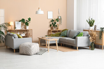 Interior of stylish living room with grey sofas, table and green plants