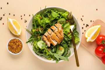 Bowl with tasty arugula salad and ingredients on beige background, closeup