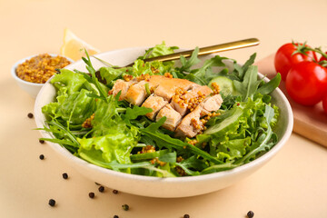 Bowl with tasty arugula salad on beige background, closeup